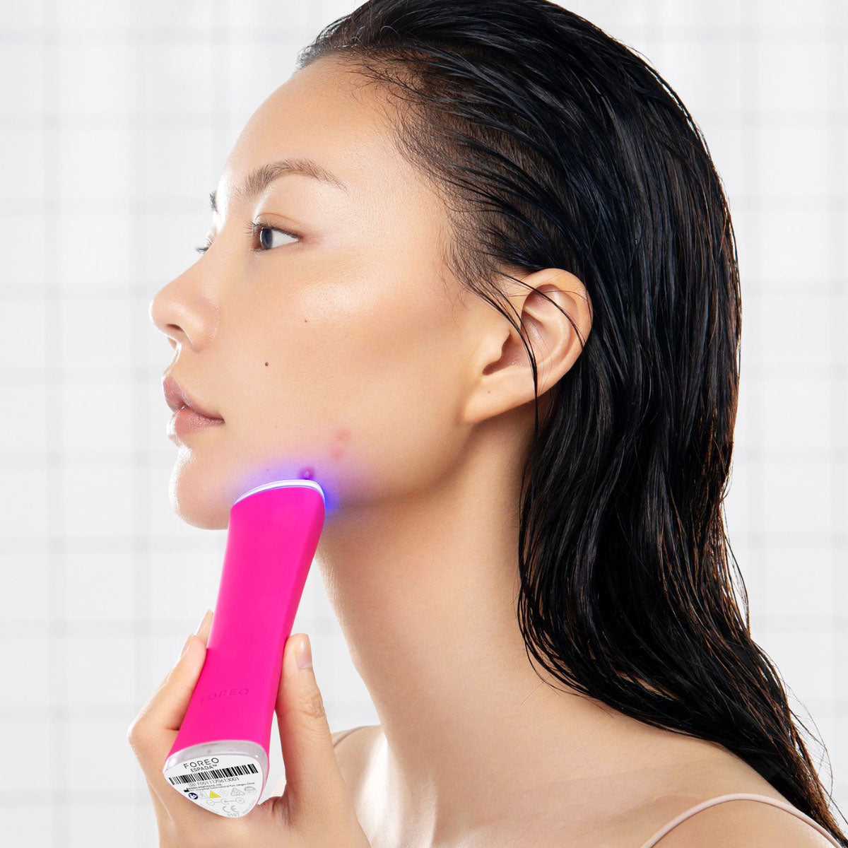 Person using Foreo Espada blue light therapy device to remove acne
